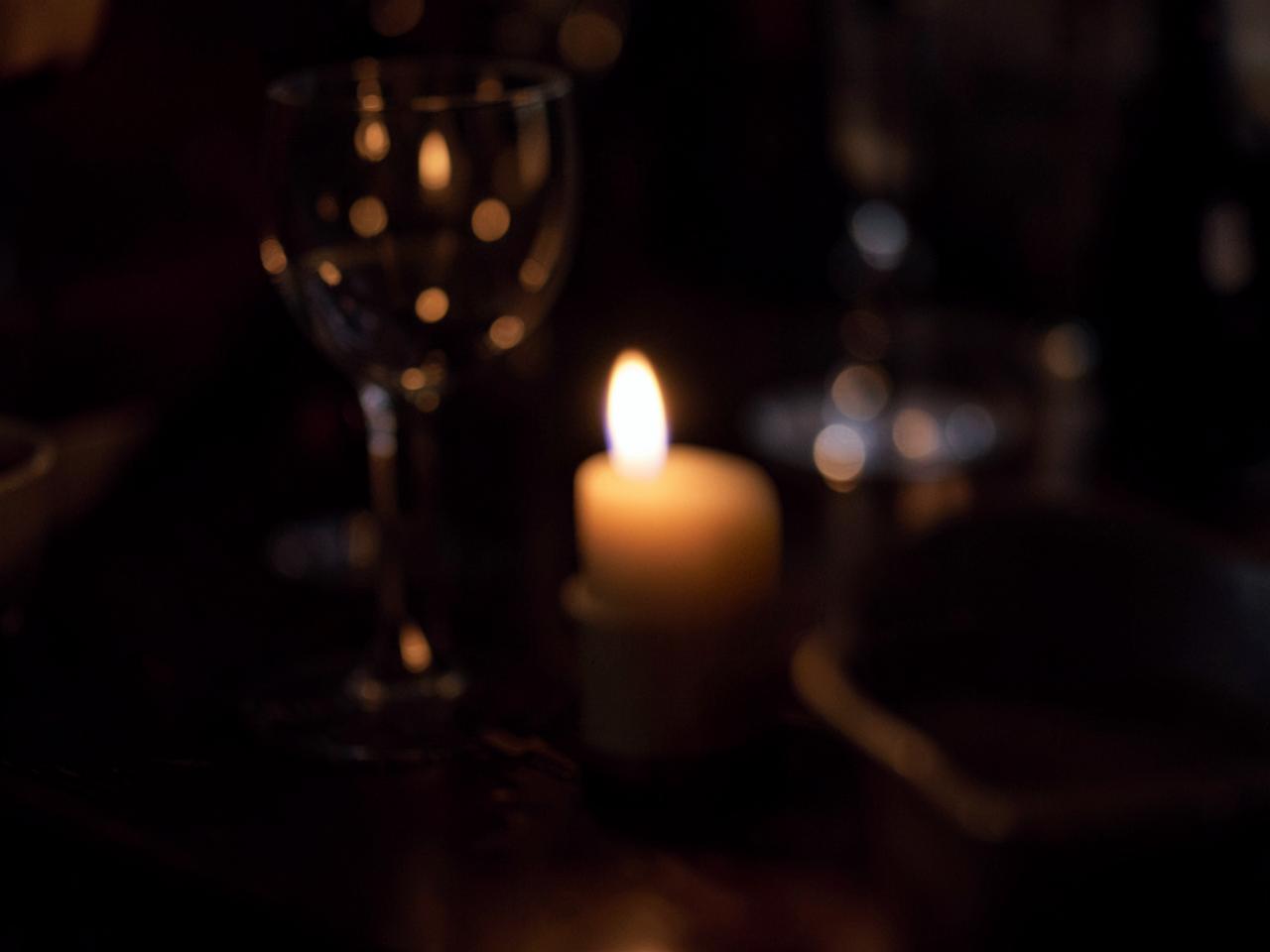 Candlelight on a dark table, softly out of focus.