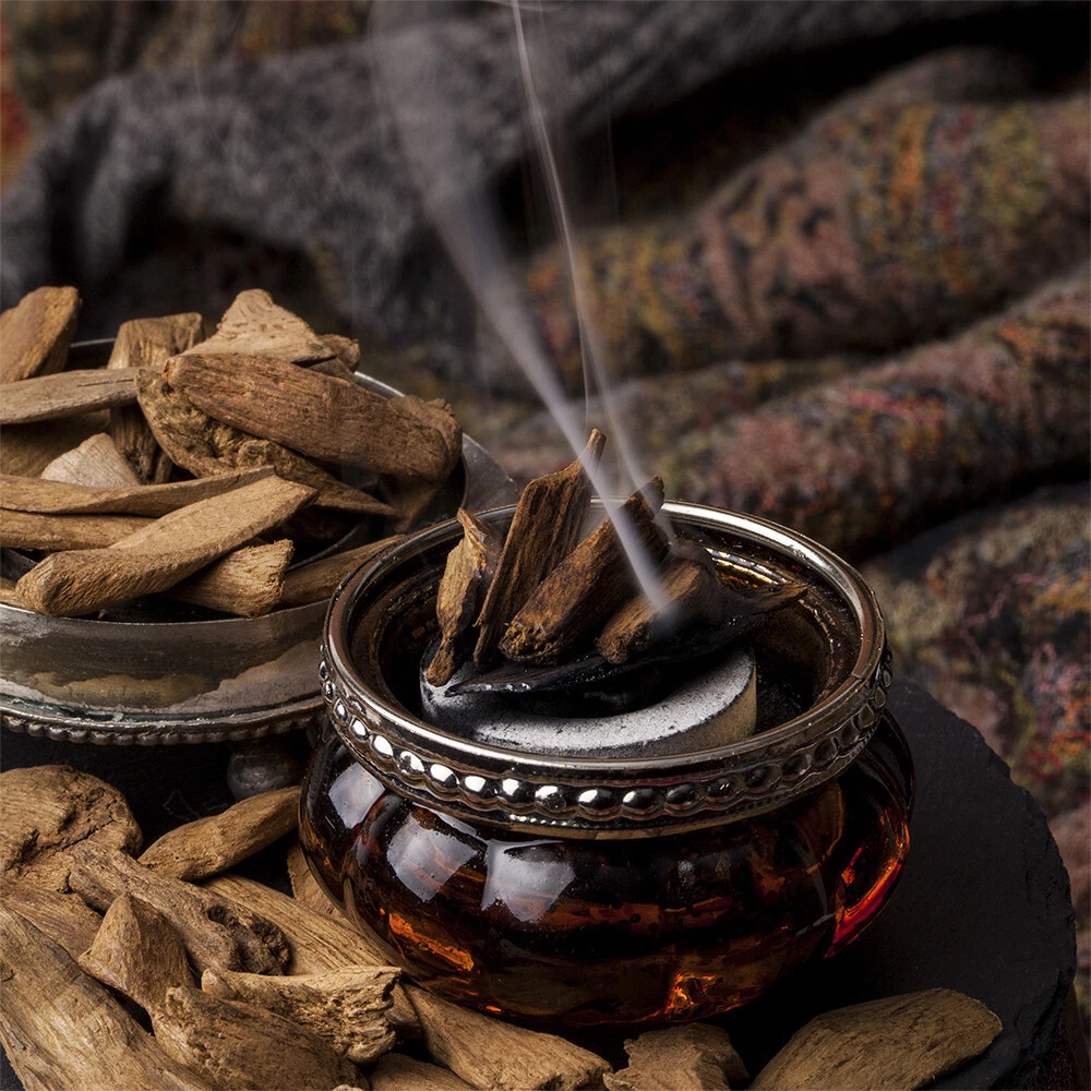 Oud wood chips smoldering in an ornate incense burner.